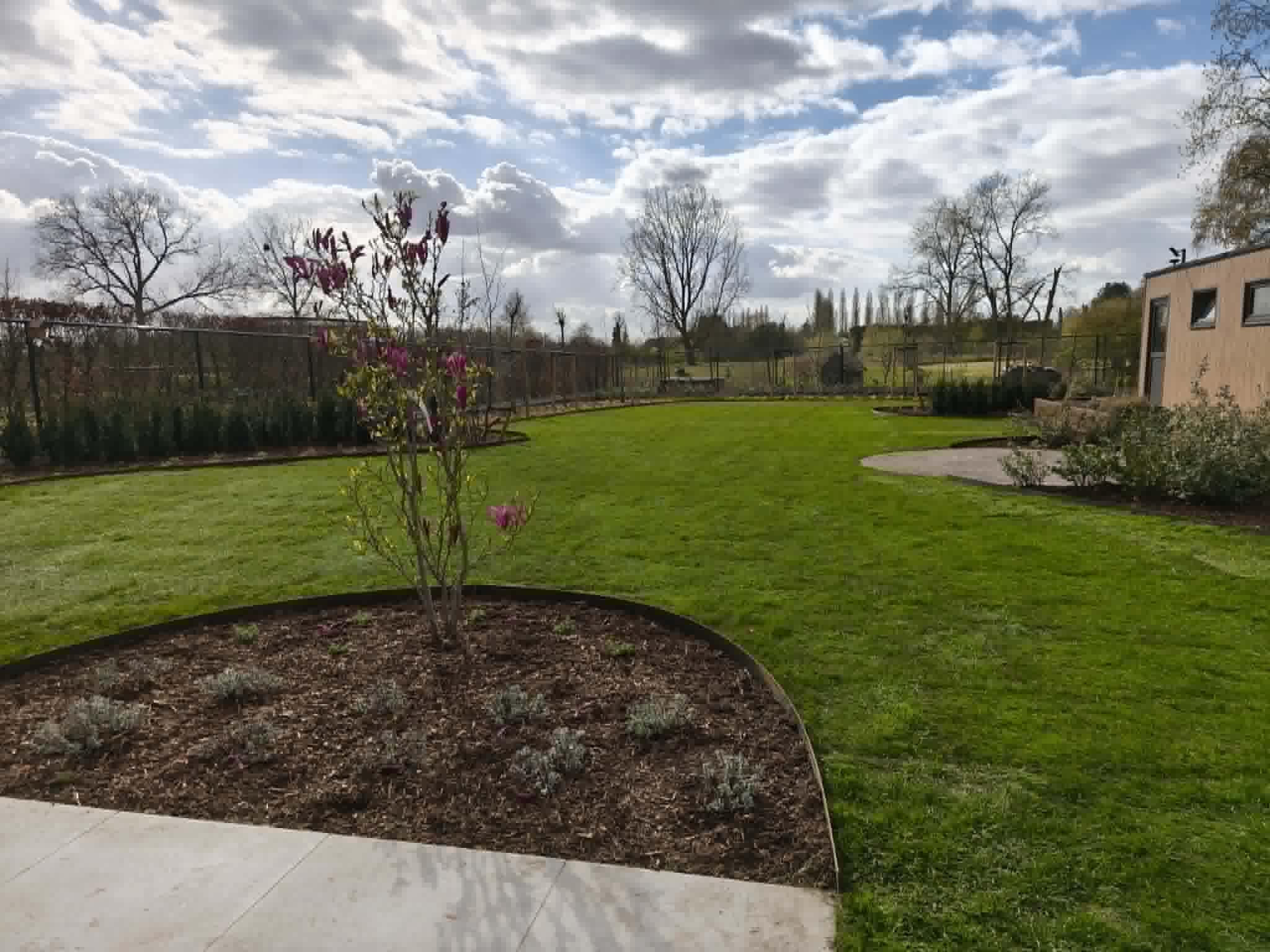 Tuinaannemer aan het werk bij vakkundige tuinaanleg en professioneel onderhoud van een verzorgde tuin met strak gemaaid gazon en gesnoeide hagen